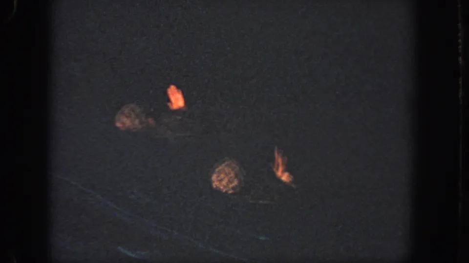 The swimmers cluster closer together in the dark pool, with caps and hands visible as the synchronized movement continues.