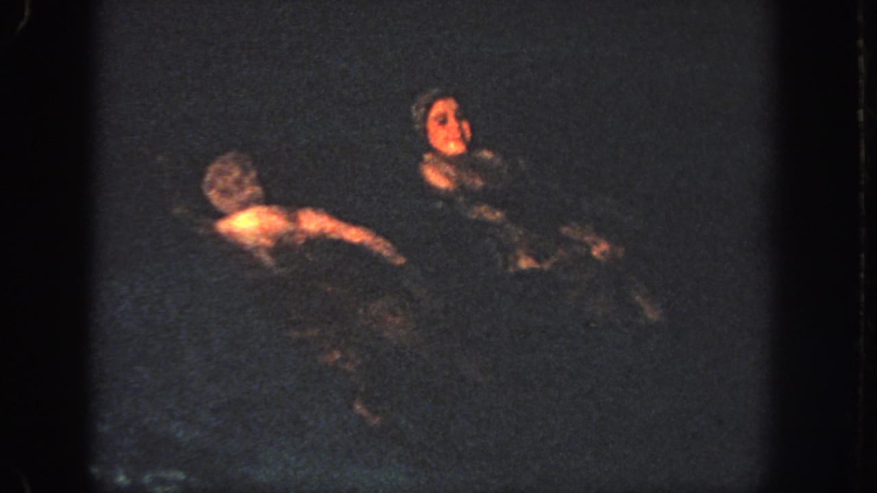 Two swimmers float near each other in a low-light Georgia pool at the end of the 1951 home-movie excerpt.