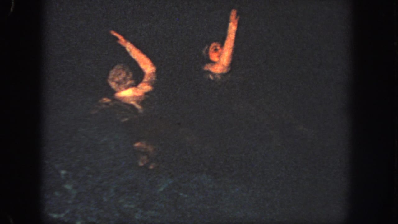 Two people appear in dark Georgia water in 1951 home-movie footage, with arms raised and faces partly lit.