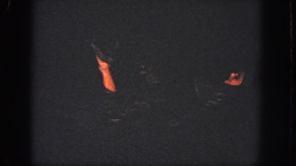 Two swimmers remain partly visible in dark water, with one raised limb and a face catching warm light near the right edge.