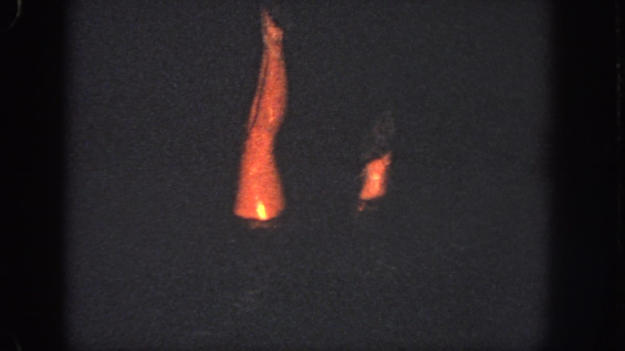 1951 Georgia 8mm frame showing dim underwater pool footage with a swimmer's orange-lit limbs emerging from darkness.