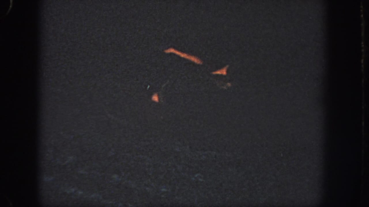 1951 Georgia pool footage with faint swimmer forms and warm highlights against dark, grainy water.