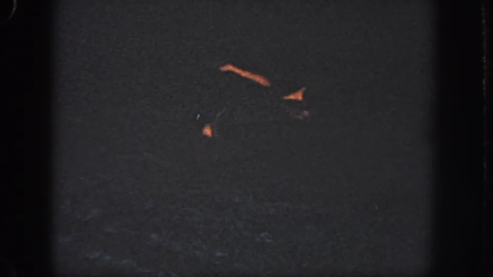 1951 Georgia pool footage with faint swimmer forms and warm highlights against dark, grainy water.