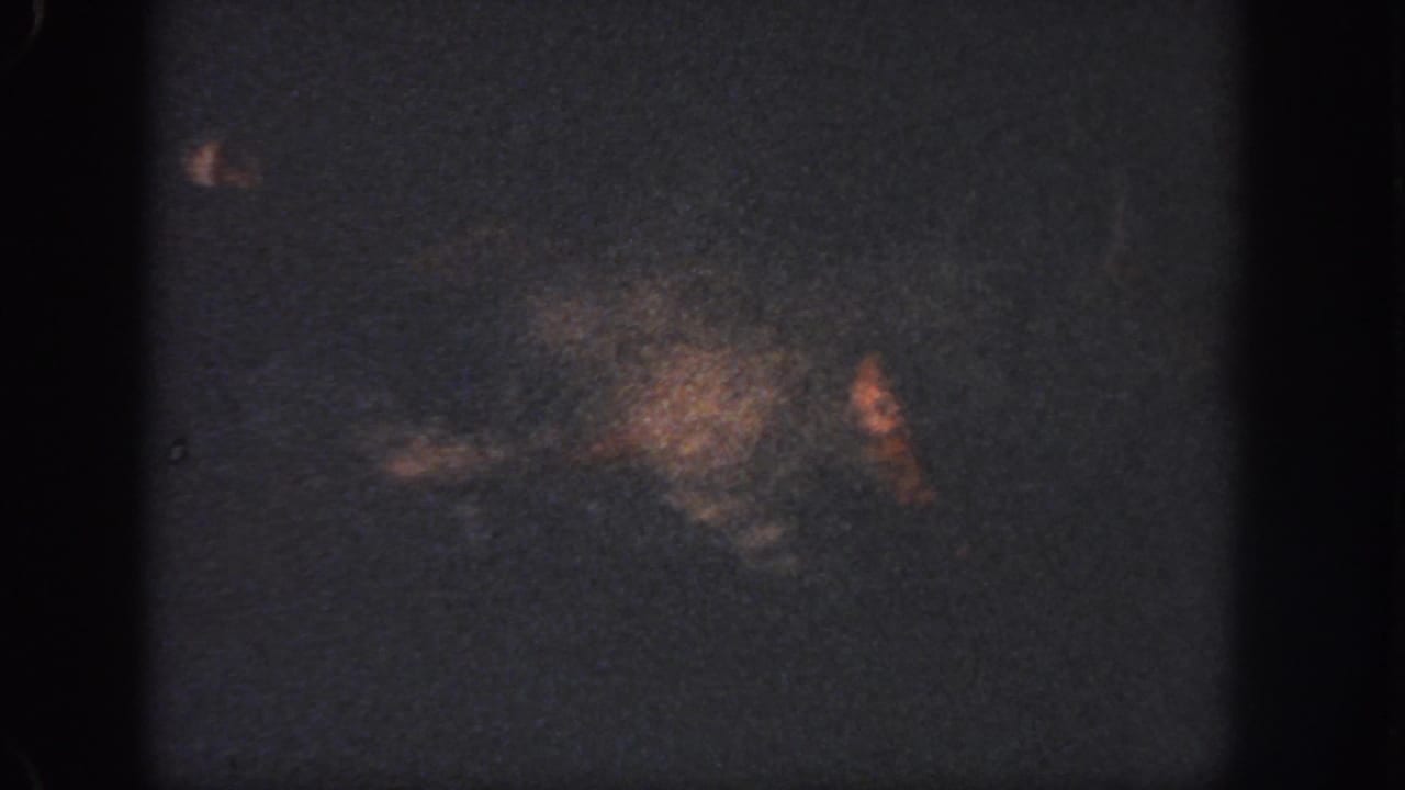 Low-light 1951 Georgia 8mm frame with dark water, soft orange-brown staining, grain, and edge shadows.