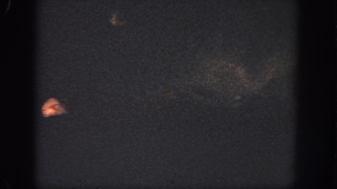 1951 Georgia 8mm frame showing murky water, faint indistinct shapes, a small orange highlight, and film wear.