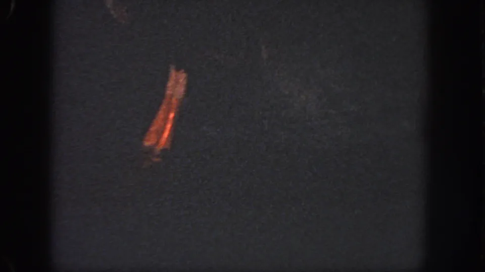 Low-exposure 1951 Georgia 8mm frame with dark water, a prominent orange-brown stain, grain, and edge shadows.