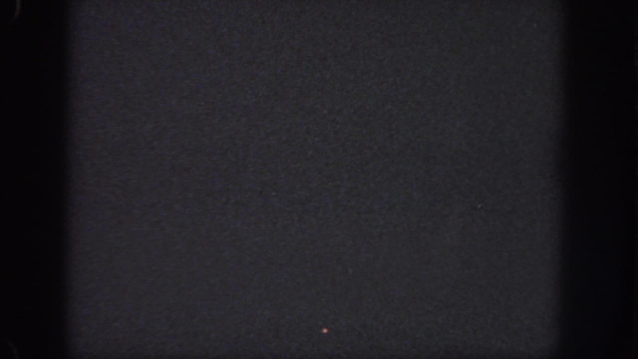 Dark 1951 Georgia 8mm frame with a faint small light speck and visible film-edge shadowing.