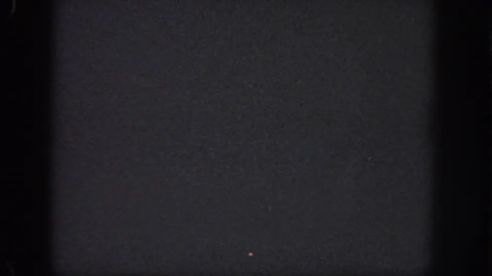 Dark 1951 Georgia 8mm frame with a faint small light speck and visible film-edge shadowing.
