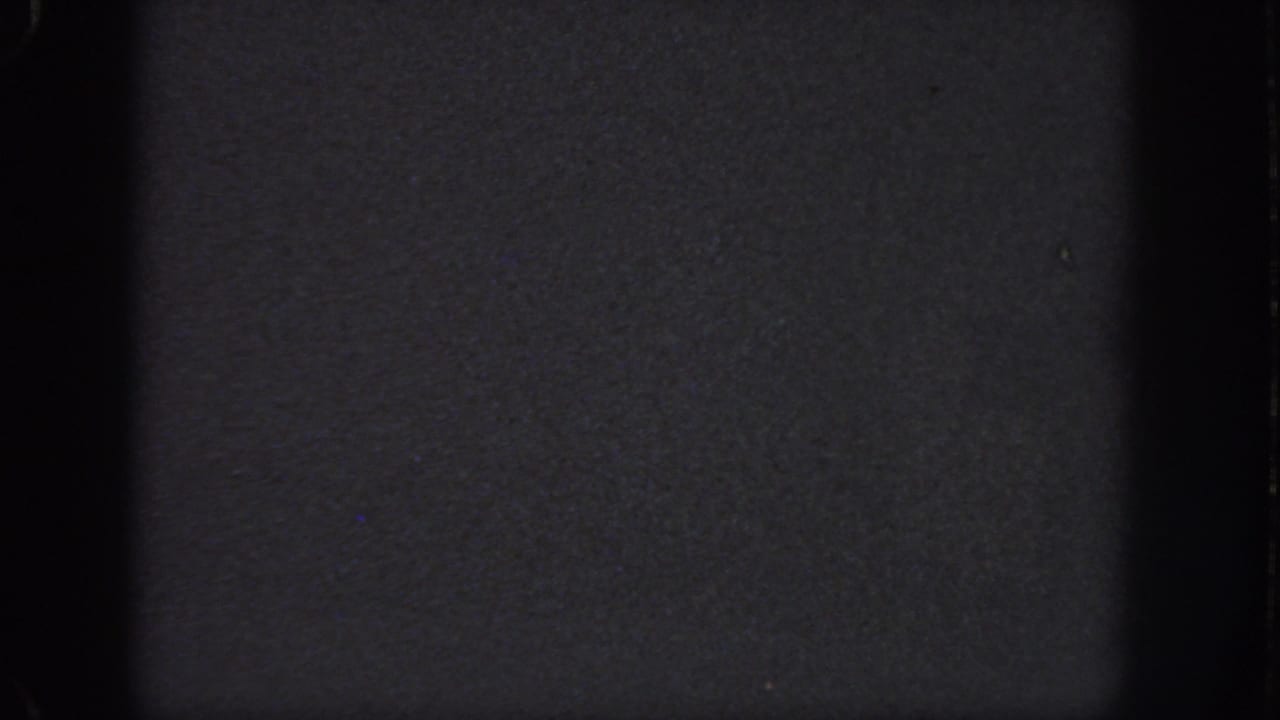 Dark color 8mm frame from the 1951 Georgia clip, showing grain, edge shadowing, and a nearly featureless surface.