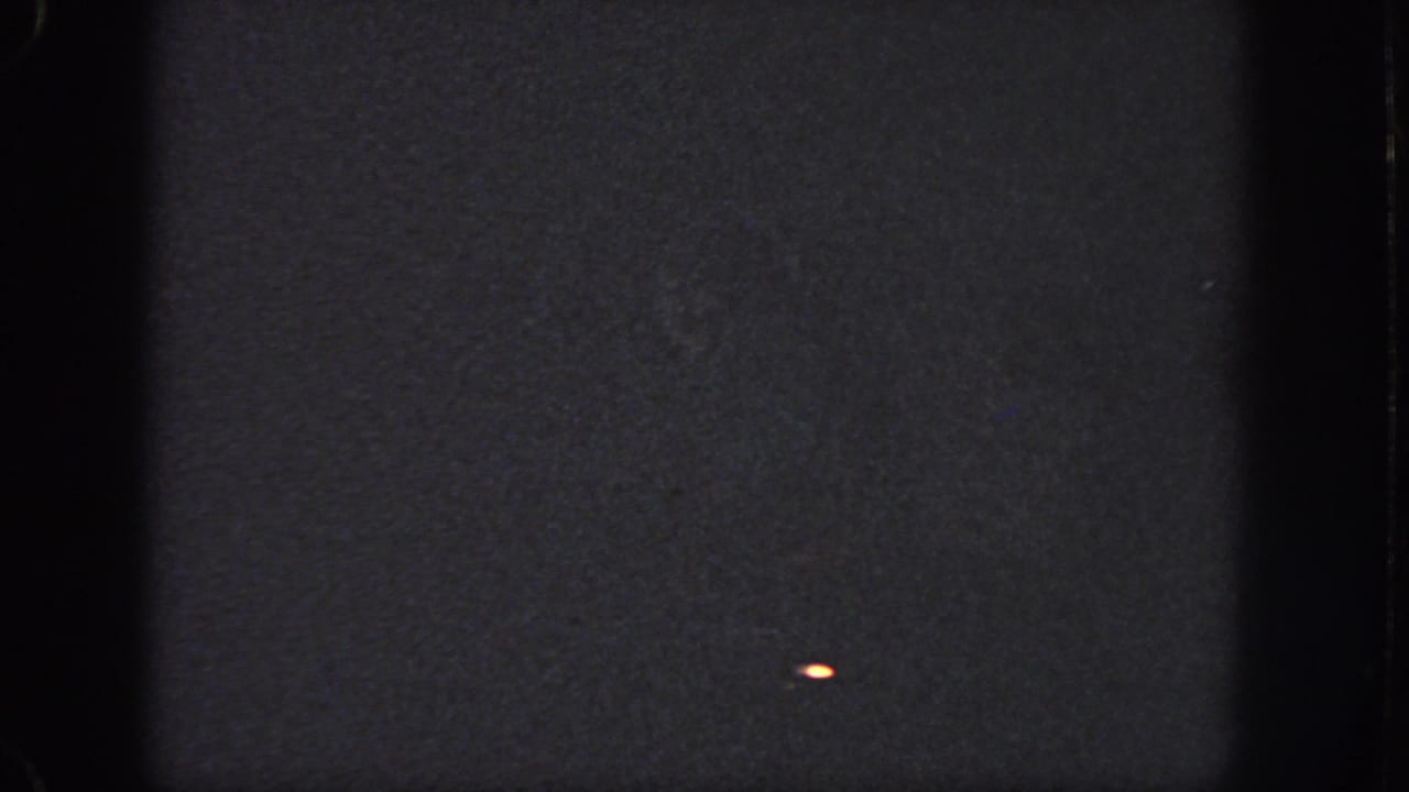 1951 Georgia 8mm frame with dark exposure, a small bright mark near the lower right, and visible edge artifacts.