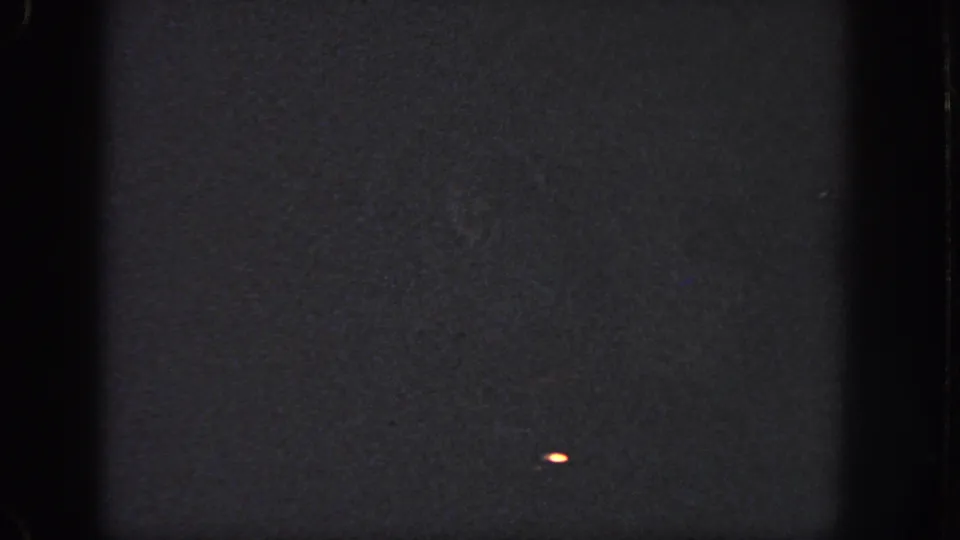 1951 Georgia 8mm frame with dark exposure, a small bright mark near the lower right, and visible edge artifacts.