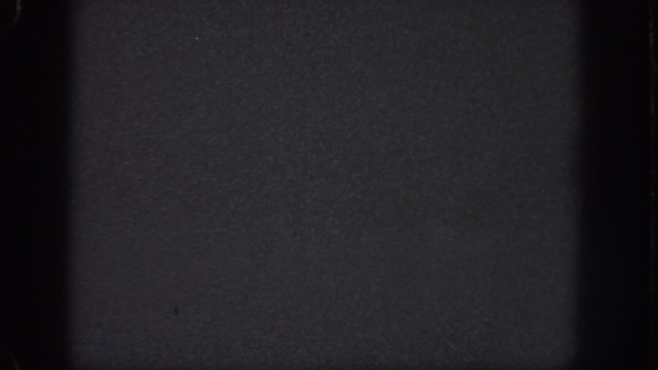 Underexposed 1951 Georgia-sourced 8mm frame showing grain, gate-edge shadowing, and a faint horizontal division.