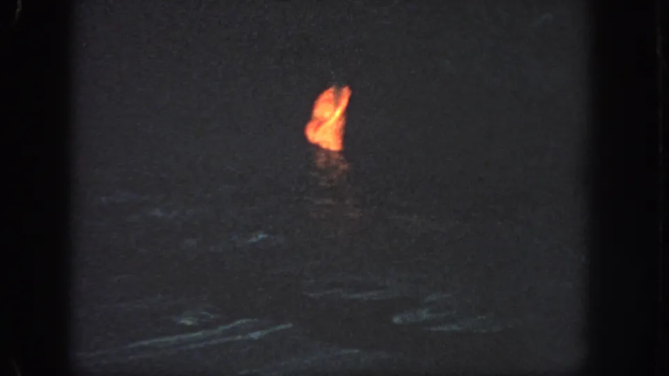 A distant person appears partly visible in dark offshore water, marked by a bright orange life jacket or flotation device.