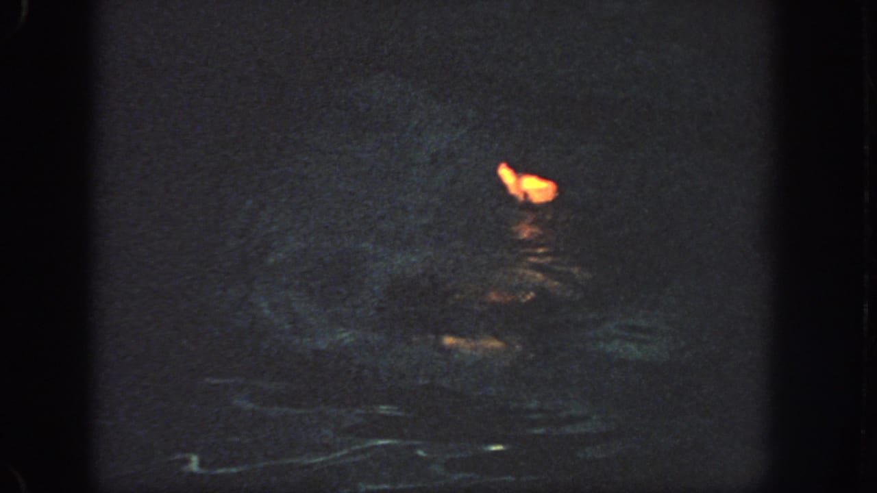 Near the end of the clip, the orange flotation shape sits low on dark water with only faint surrounding detail visible.