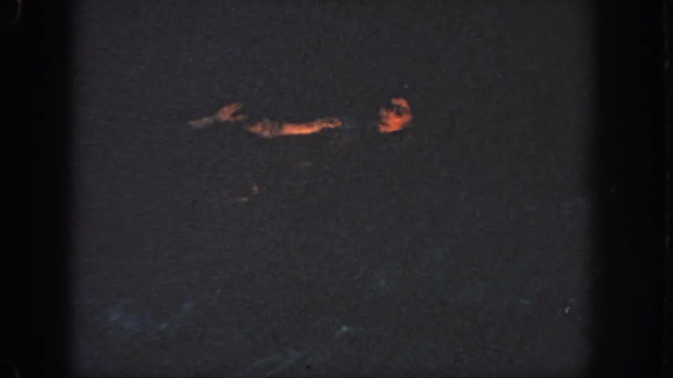 1951 Georgia home-movie frame of a woman in a dark pool, seen in partial profile with one arm extended across the water.
