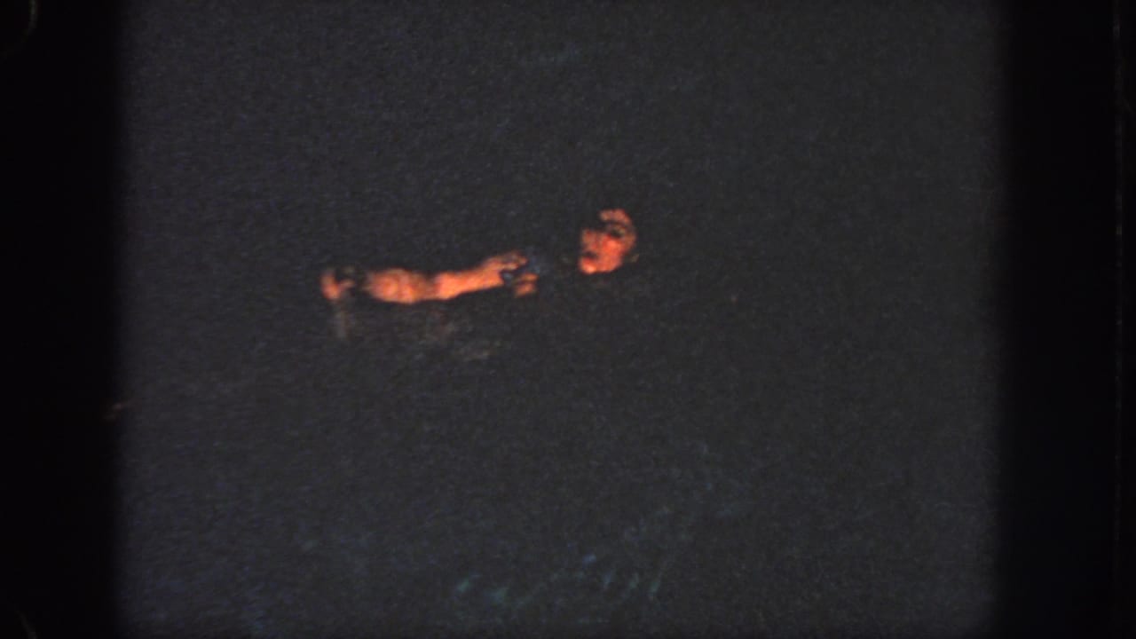 1951 Georgia 8mm frame showing the swimmer lower in the dark pool, with her face and arm softly lit against the water.