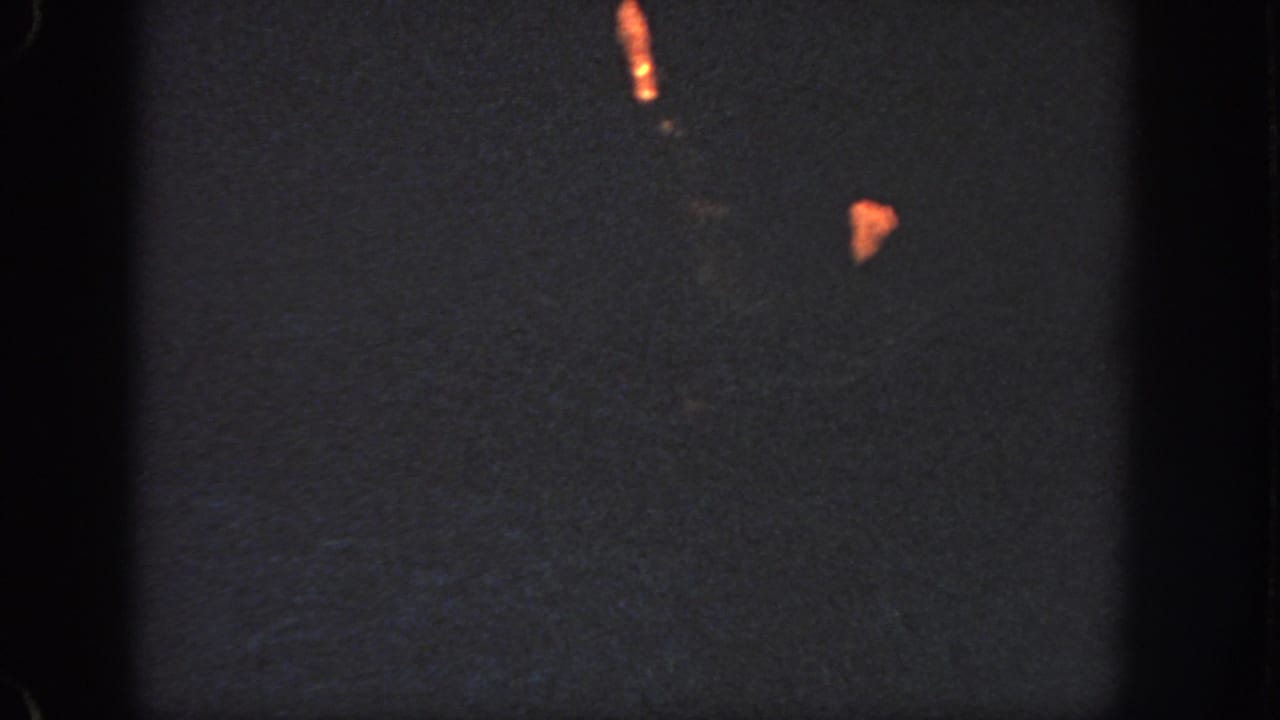 1951 Georgia 8mm frame showing a female swimmer partly visible in a dark pool, lit by warm orange highlights.