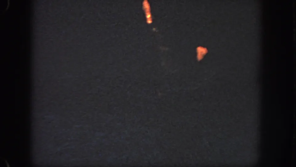 1951 Georgia 8mm frame showing a female swimmer partly visible in a dark pool, lit by warm orange highlights.