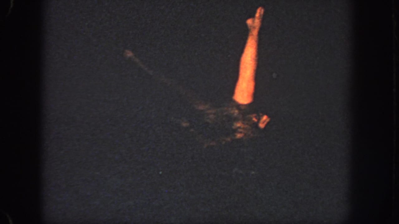 1951 Georgia home-movie frame showing a woman in a swim cap and dark suit extending one arm above the pool surface.