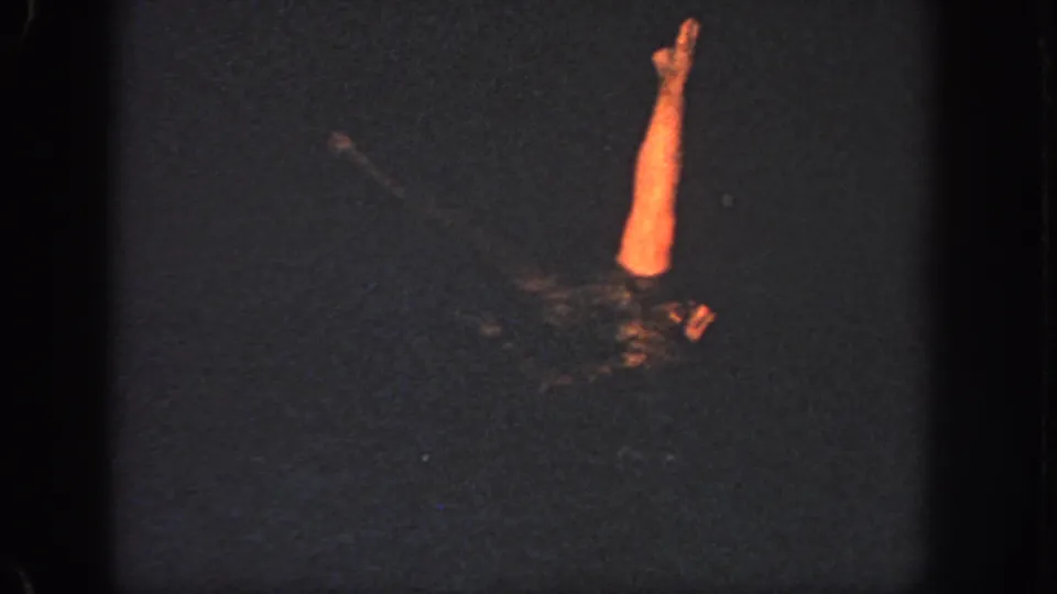 1951 Georgia home-movie frame showing a woman in a swim cap and dark suit extending one arm above the pool surface.