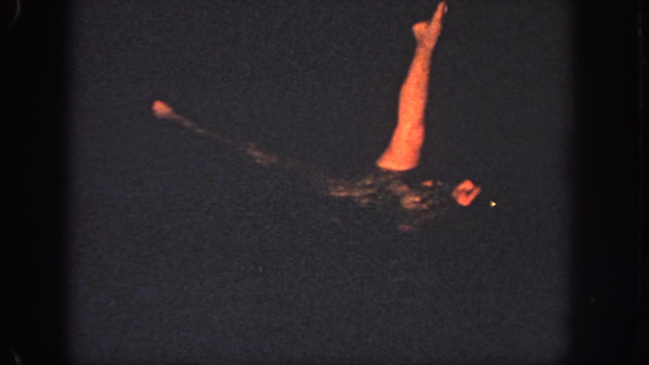 1951 Georgia 8mm frame of a woman in a swim cap practicing a controlled pool movement with one arm lifted.