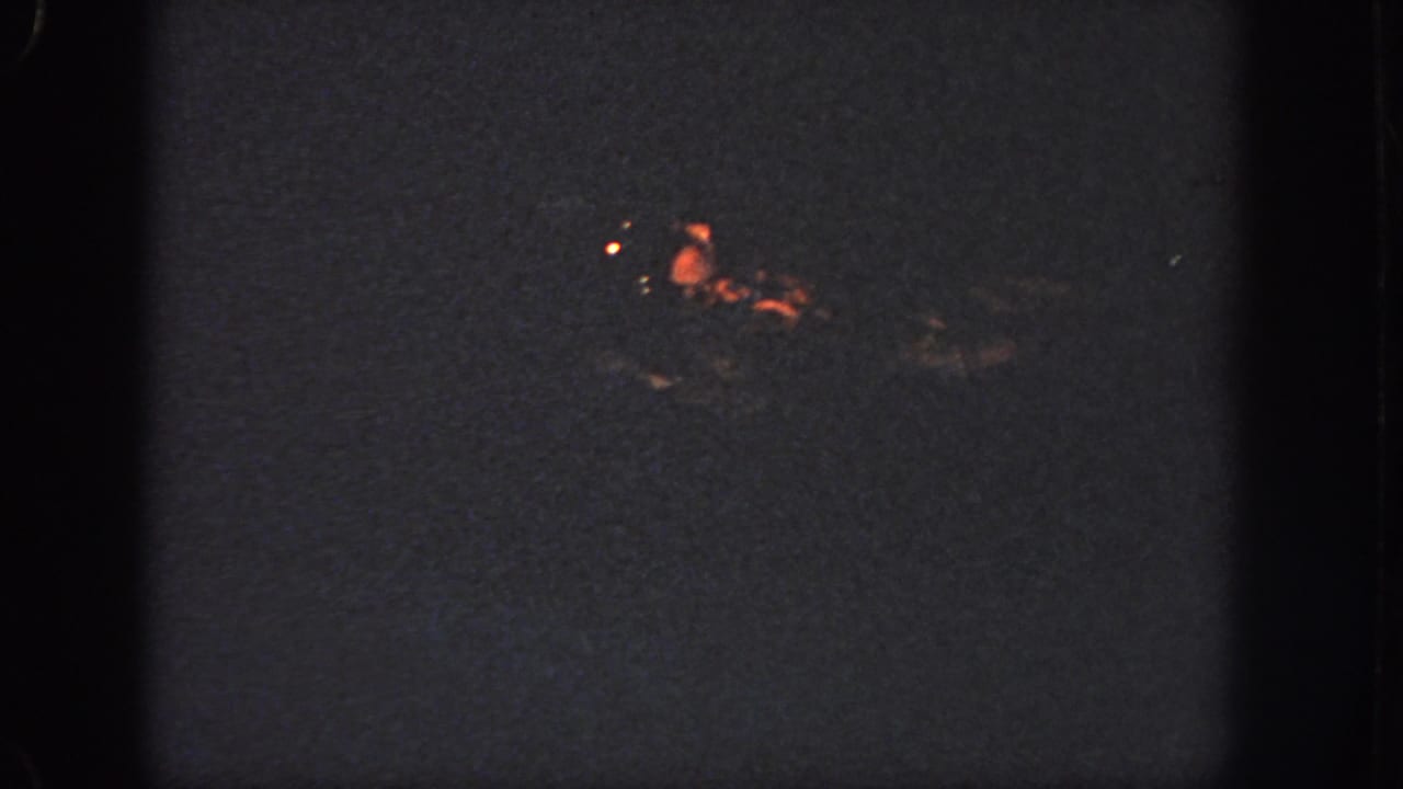 A distant swimmer glints in orange light on dark water in this grainy 1951 Georgia home-movie frame.