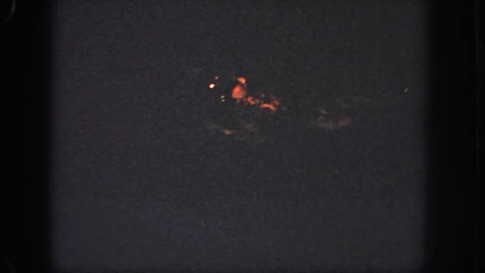 A distant swimmer glints in orange light on dark water in this grainy 1951 Georgia home-movie frame.