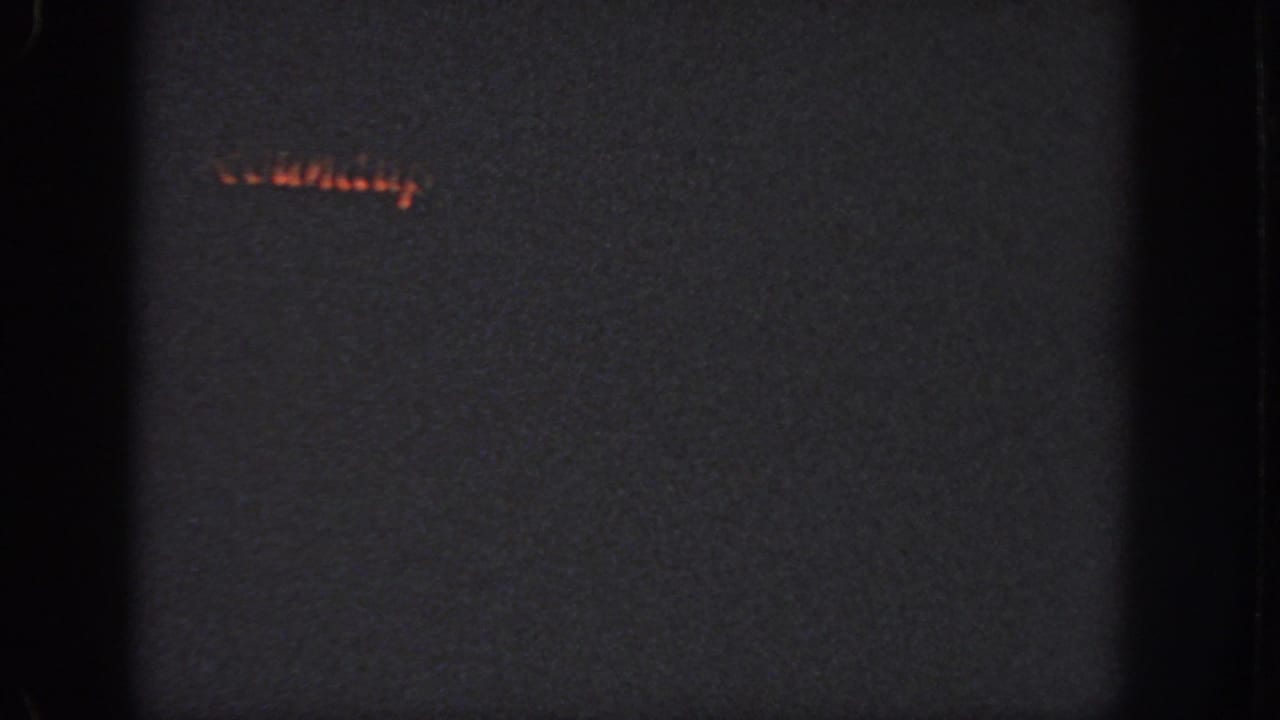 Low-light 8mm frame from Georgia, 1951, with a small orange glow and little visible scene detail.