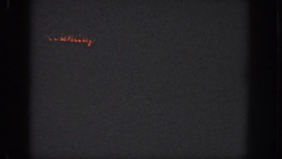 Low-light 8mm frame from Georgia, 1951, with a small orange glow and little visible scene detail.