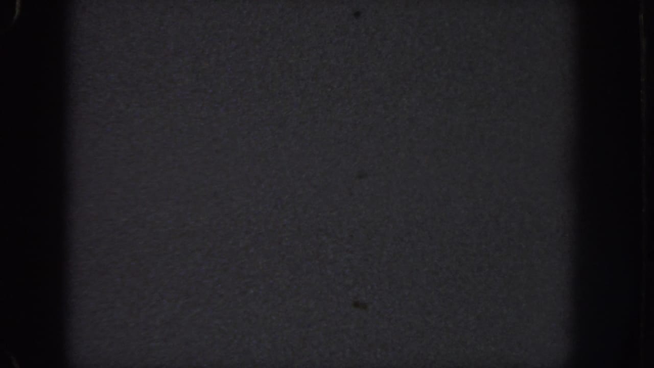 Dark 8mm frame with grain, vignetting, and vertical film edges.