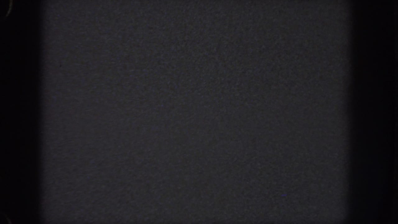 Nearly black 1951 Georgia 8mm frame showing film texture, shadowed edges, and no visible figures or setting.