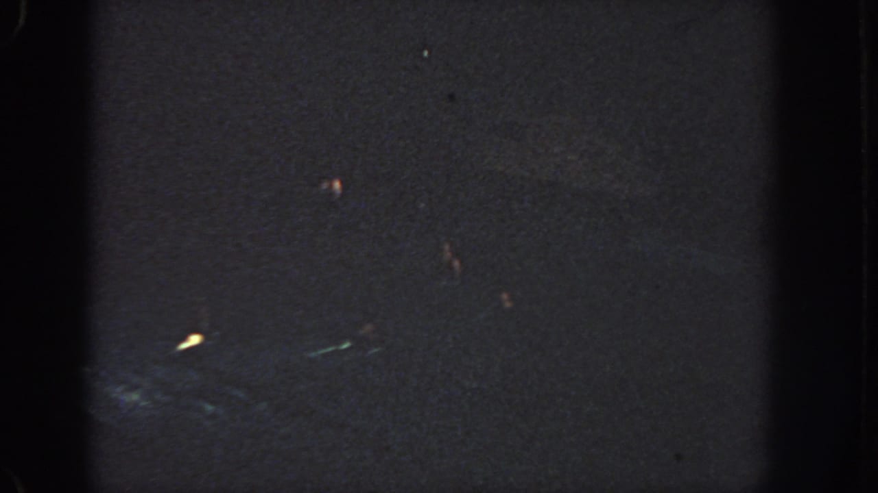 1951 Georgia 8mm night frame with small light streaks in the lower half, surrounded by darkness and grain.