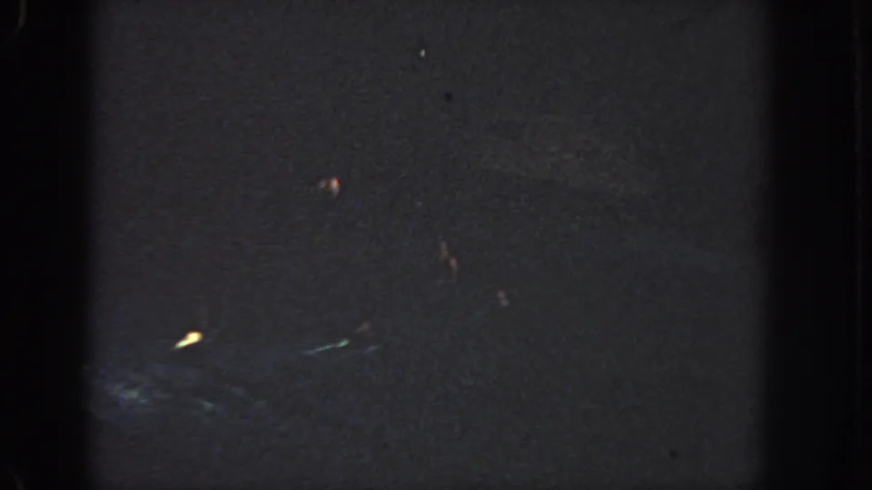 1951 Georgia 8mm night frame with small light streaks in the lower half, surrounded by darkness and grain.