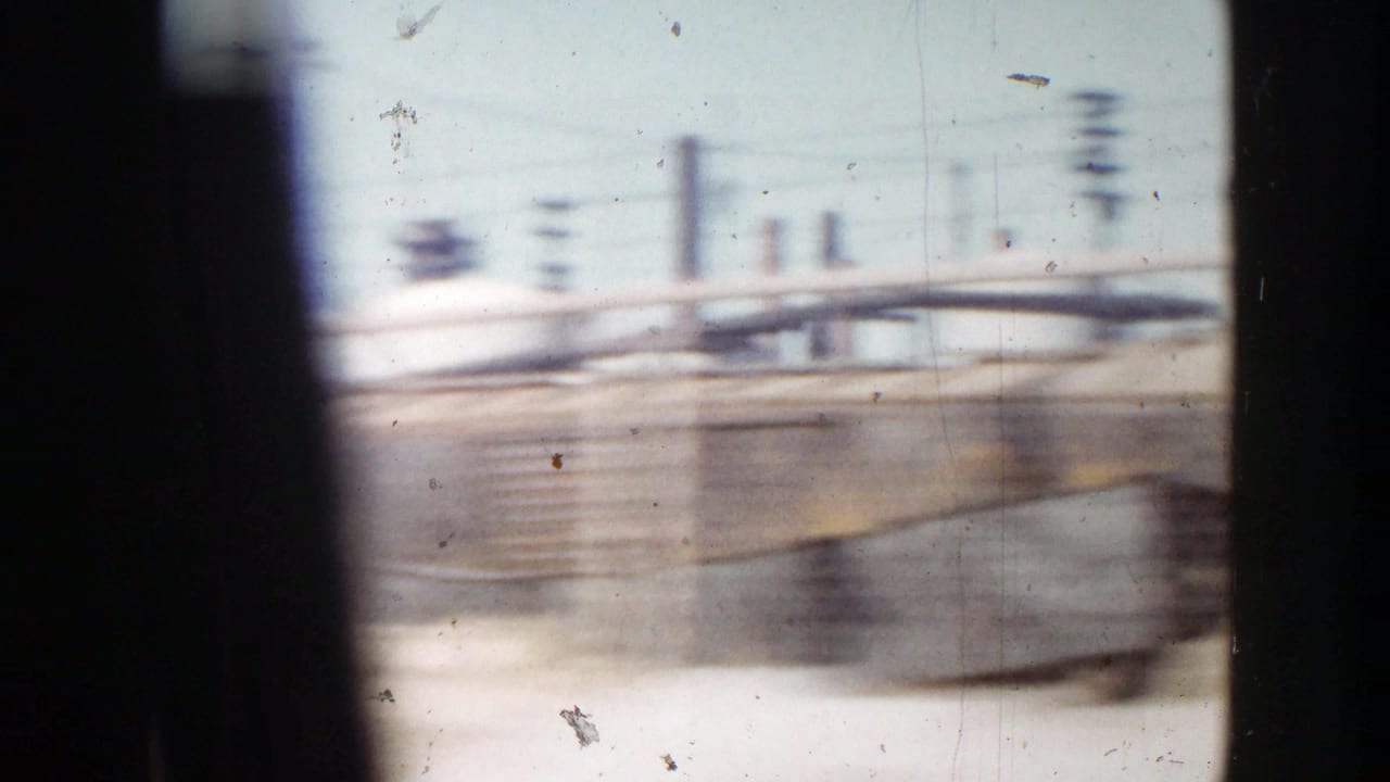 A fast 1956 Grand Rapids street view with utility poles, railings, and industrial roadside elements blurred by motion.
