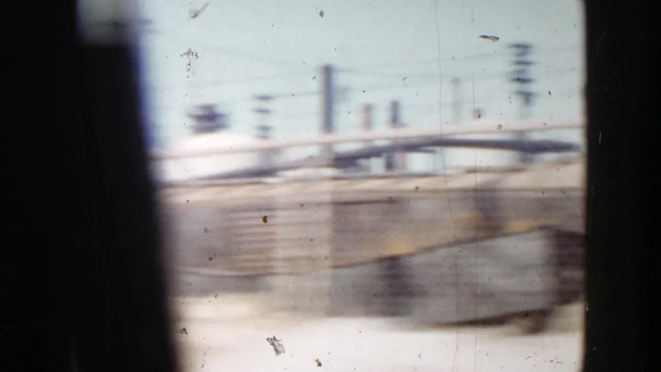 A fast 1956 Grand Rapids street view with utility poles, railings, and industrial roadside elements blurred by motion.