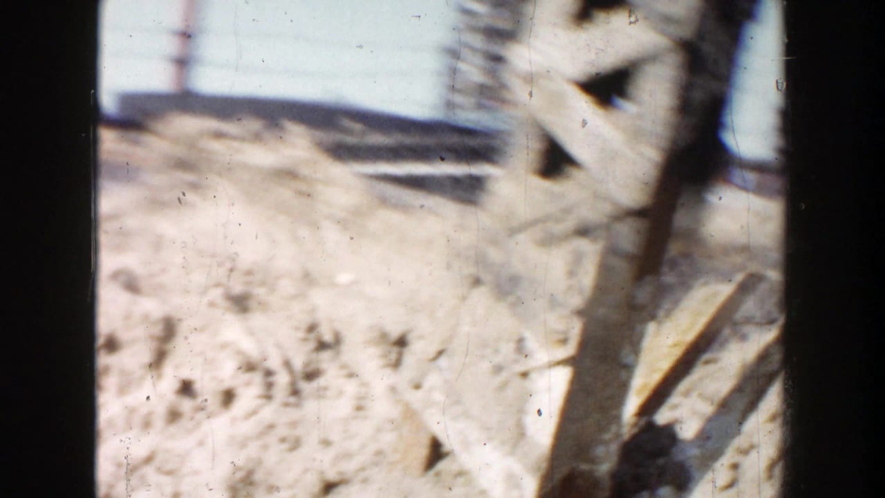 Close view of pale steel beams and dirt with utility lines behind them.