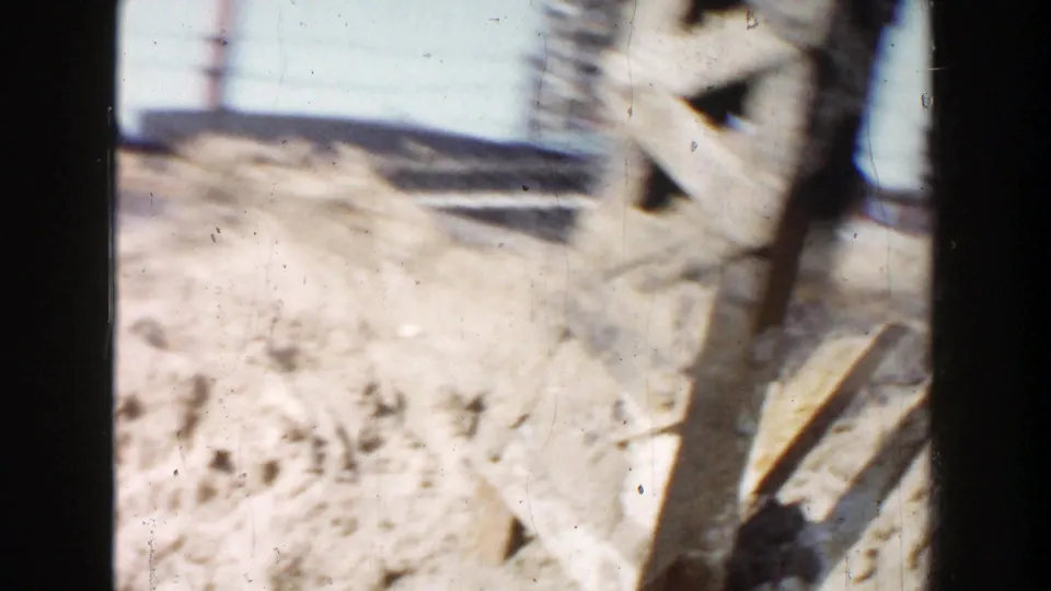 1956 Grand Rapids 8mm frame with structural steel beams crossing the view near a dirt mound and overhead lines.