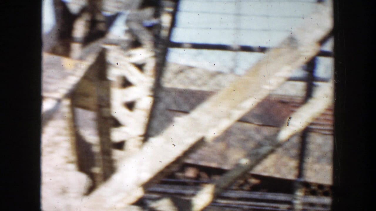 1956 Grand Rapids 8mm frame with angled steel braces, a fence line, and scattered industrial construction material.