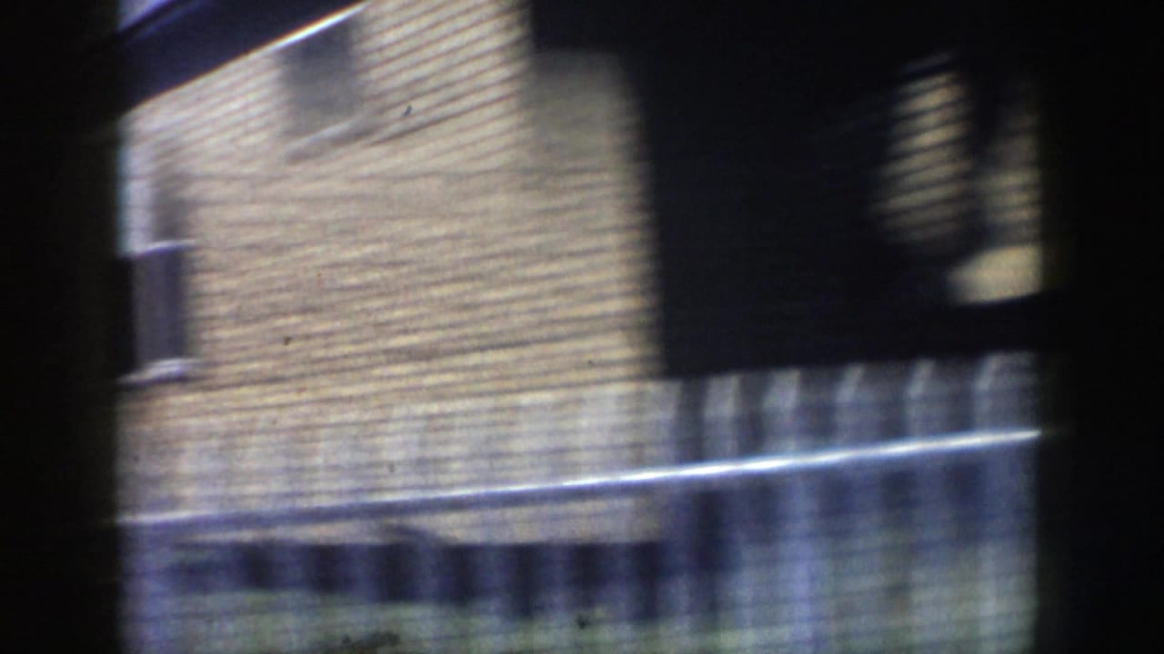 Brick building exterior and railing seen in motion from inside a vehicle.