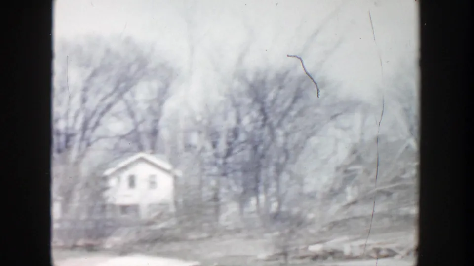 1956 Grand Rapids frame showing a small light house, leafless trees, and muted late-winter or early-spring ground.