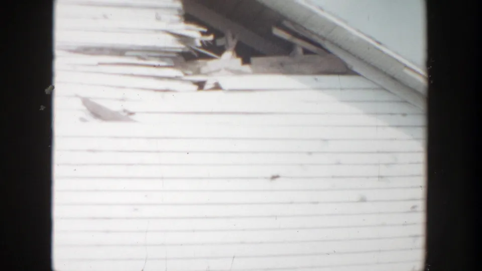 Close 1956 home-movie view of weathered siding, trim, and roof-edge details on the Grand Rapids house exterior.