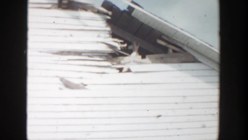 Soft 8mm frame from Grand Rapids showing clapboard siding, roofline trim, and weathered boards on the house exterior.