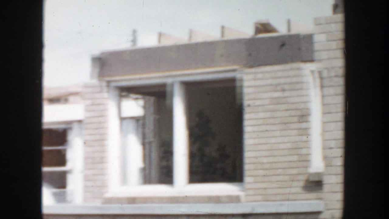 1956 Grand Rapids 8mm frame showing a brick residential facade with upper windows and soft handheld framing.
