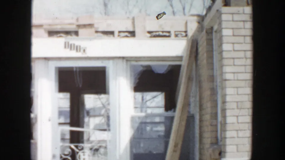 1956 Grand Rapids 8mm frame showing shattered lower windows, porch framing, and a dark exposed interior.