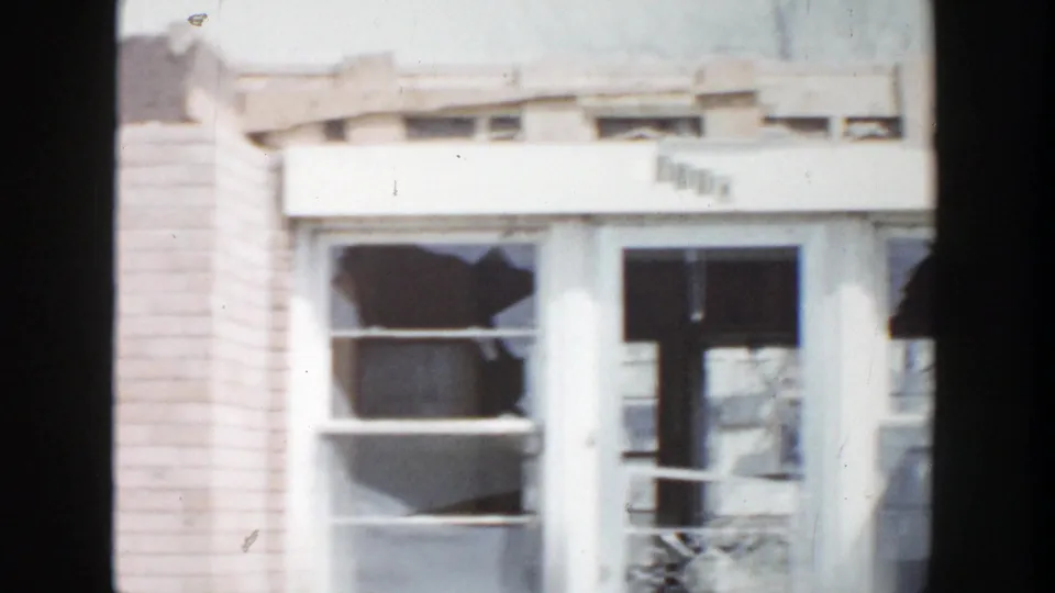 1956 Grand Rapids frame with multiple broken panes and dark openings across the lower brick facade.