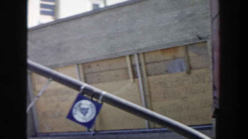 Grand Rapids storefront detail showing boarded windows, diagonal metal supports, and a small blue hanging sign.