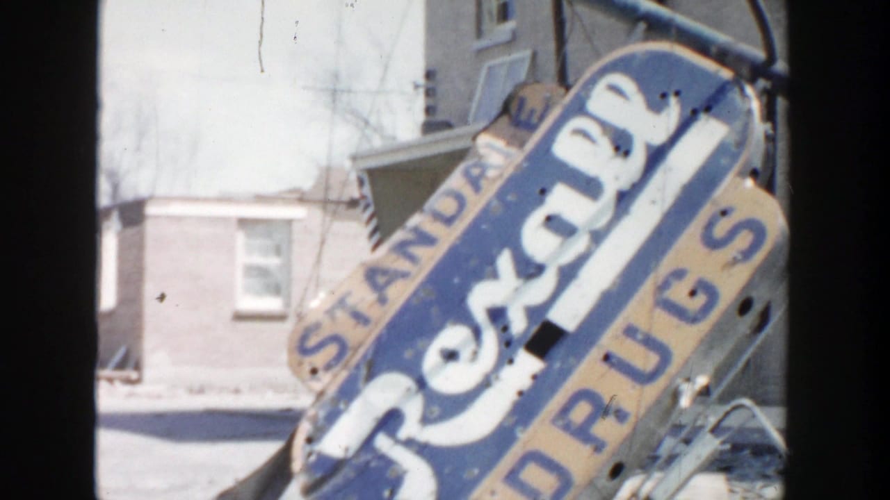 Leaning blue Rexall Drugs sign beside a pale building exterior.
