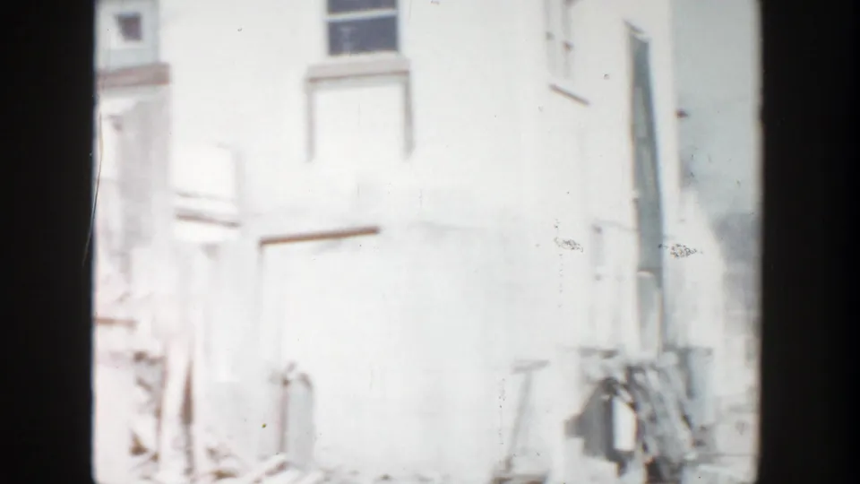 Bright 1956 Grand Rapids view of a pale building wall near the damaged Rexall sign location.