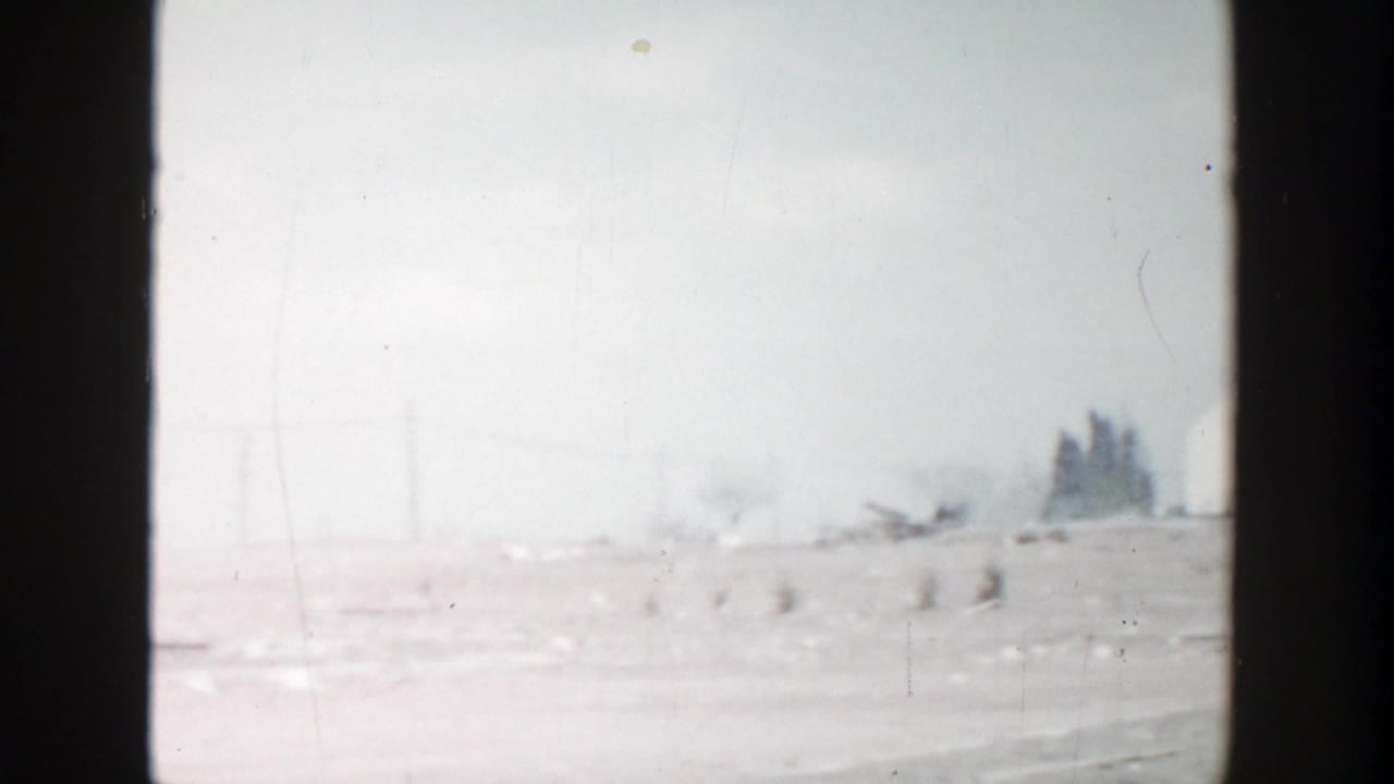 1956 Grand Rapids home-movie frame showing a hazy roadside landscape with utility poles and open ground before the car enters view.