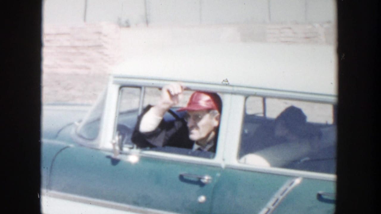 In 1956 Grand Rapids home-movie footage, an older man in a red cap waves from the driver's window of a green and white station wagon.